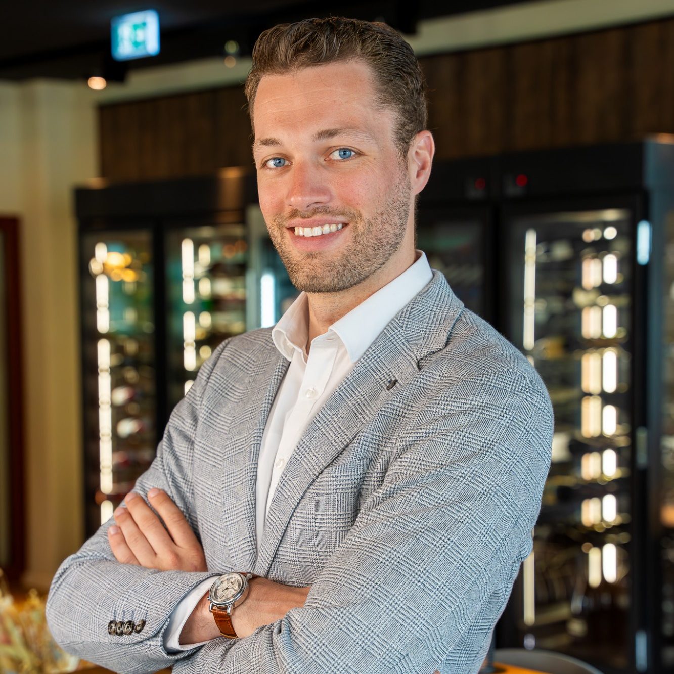 Julian Haug Julian Haug in einem Anzug, arms crossed, vor einem Verkaufsregal.